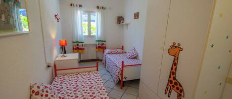 Een kinderkamer met een bed, een bureau en een raam met gordijnen.