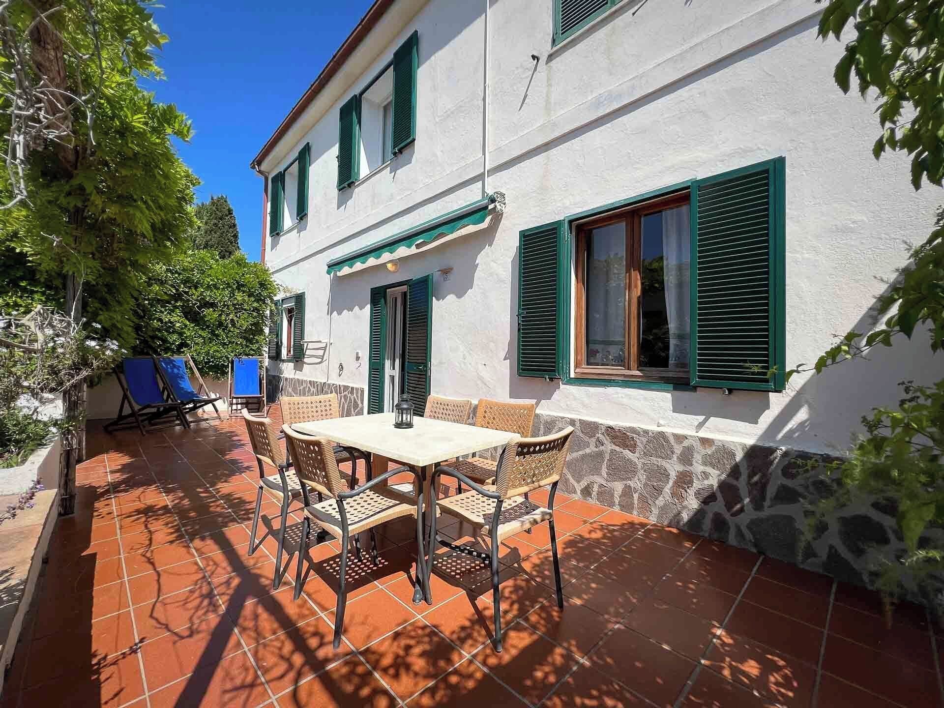 Un patio con una mesa, sillas y una pared de piedra.