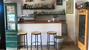 A kitchen with a bar area, stools, a refrigerator, and various kitchen appliances. - Azienda Agricola Sapereta (Porto Azzurro)
