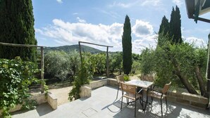 An outdoor patio with a table and chairs, surrounded by greenery and trees. - Azienda Agricola Sapereta (Porto Azzurro)