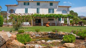 A two-story house with a garden, a pond, and outdoor furniture. - Azienda Agricola Sapereta (Porto Azzurro)