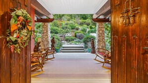 A wooden entrance with rocking chairs and a stone pathway leading to a garden. - Luxury Riverfront Paradise Escape (Three Rivers)