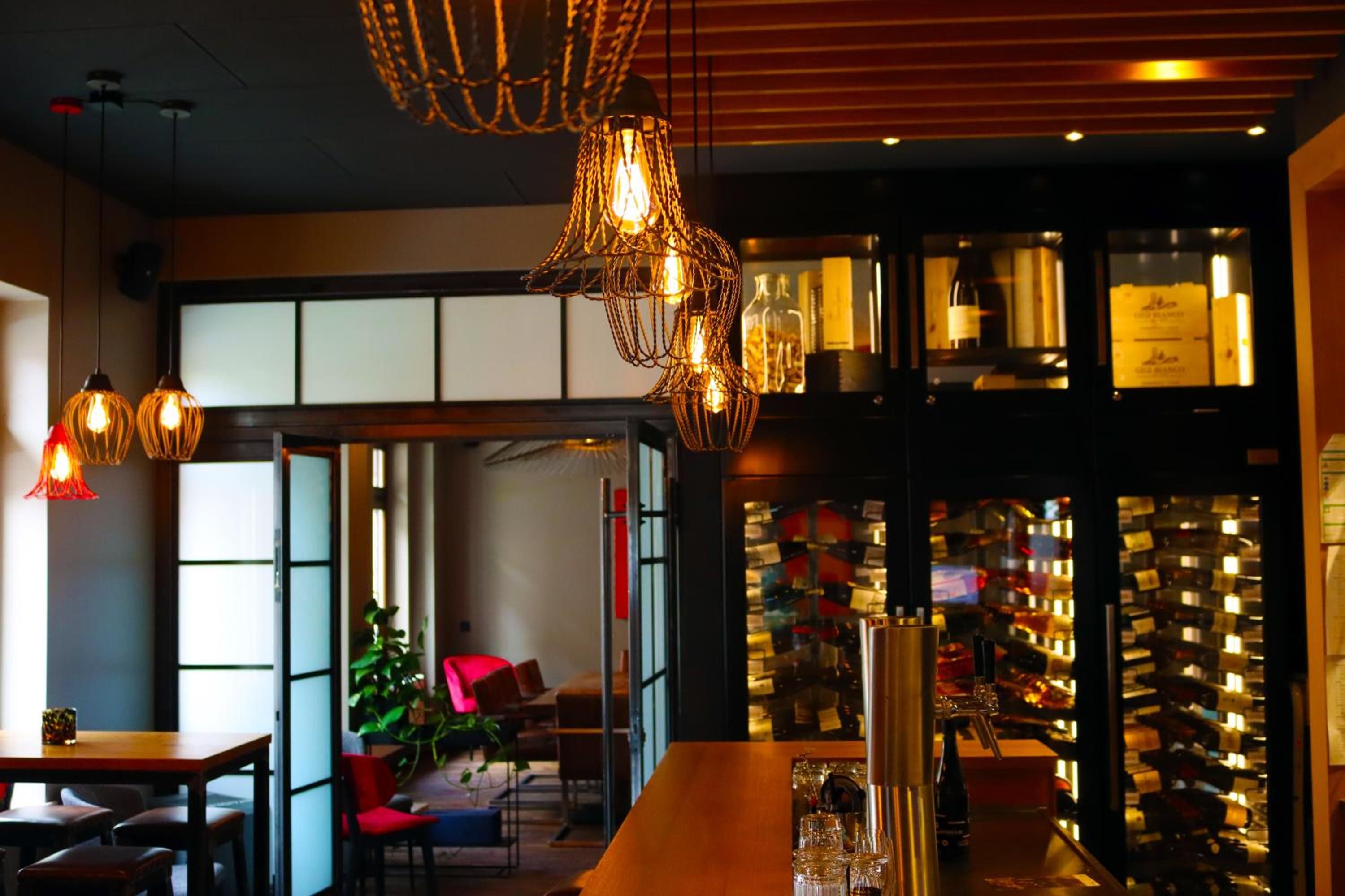 A modern interior with hanging light fixtures, a bar area, and a seating space with a view.