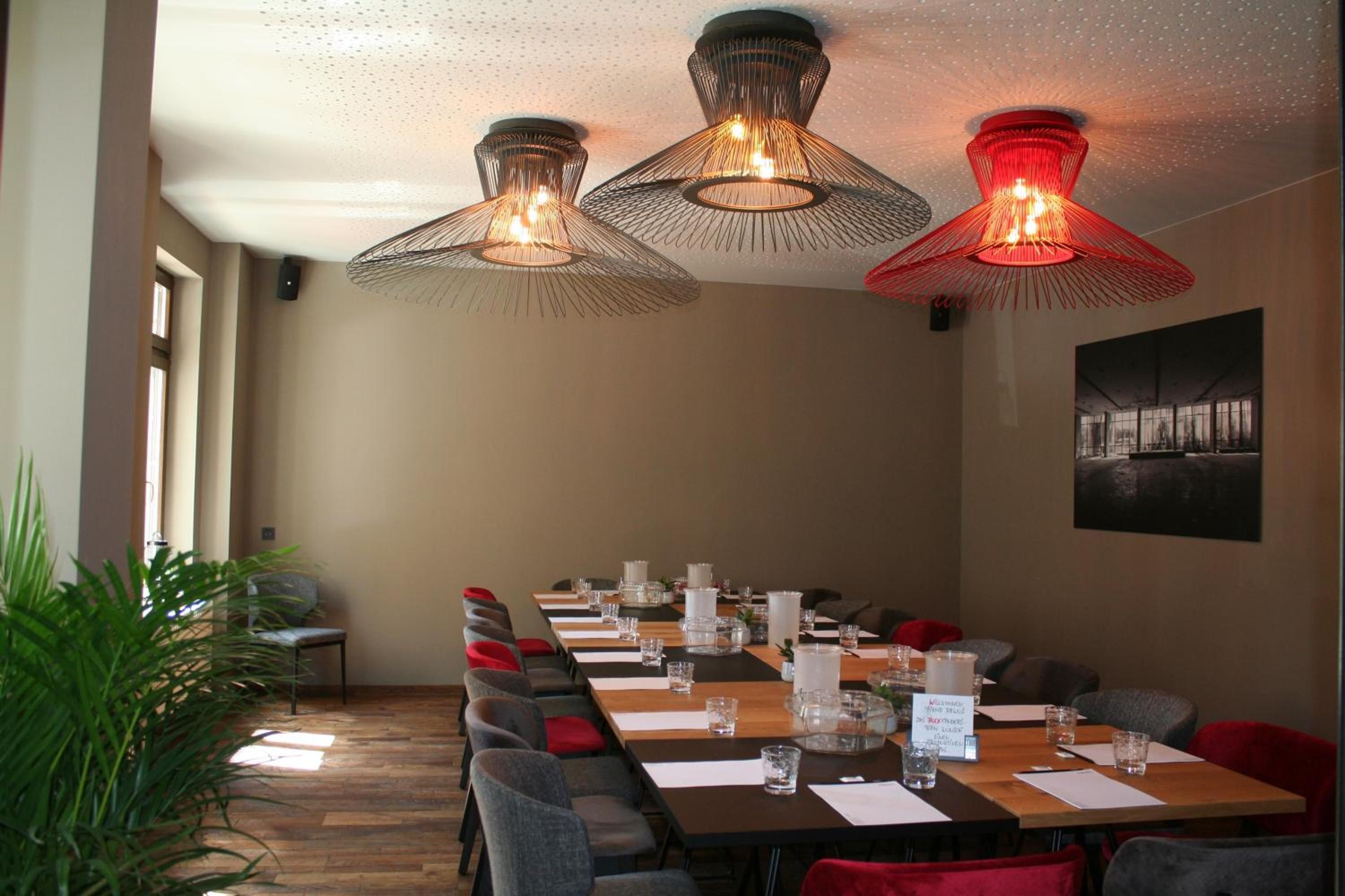 A conference room with a long table, chairs, and hanging pendant lights.