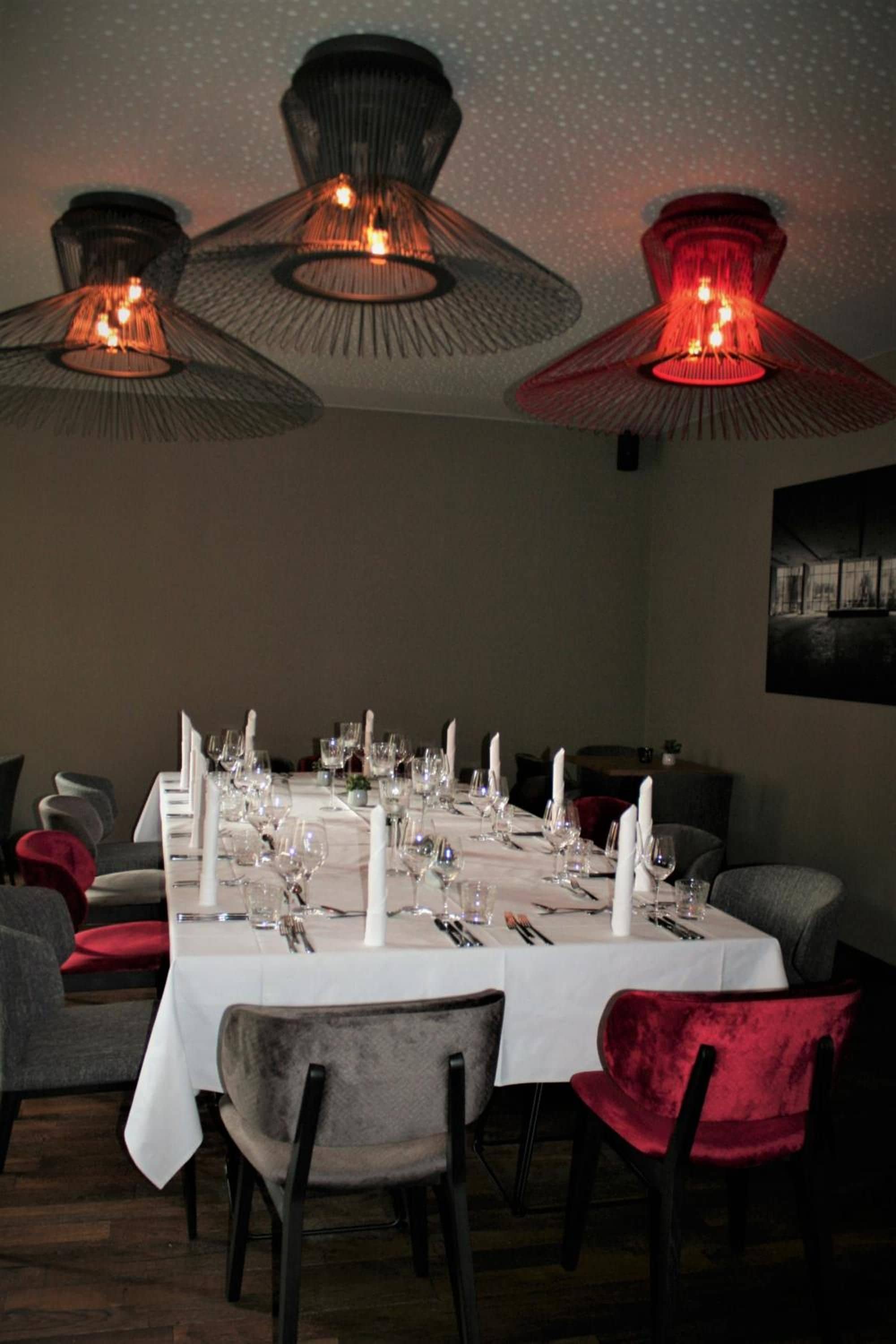 A dining room with a long table set for a meal, surrounded by chairs.