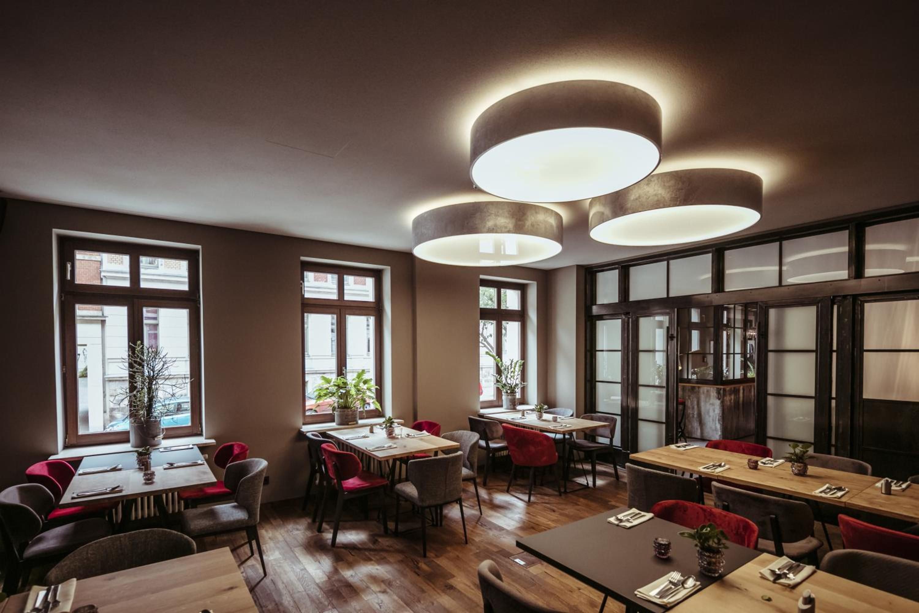 Un interior de restaurante con varias mesas, sillas y lámparas colgantes.