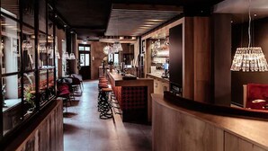A bar area with wooden counters, stools, and hanging lights. - Alexxanders Restaurant & Bordinghouse (Chemnitz)