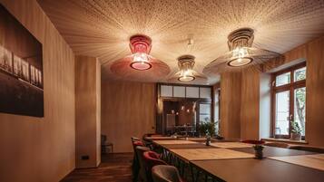 Un salón de conferencias con una larga mesa, sillas e iluminación colgante.