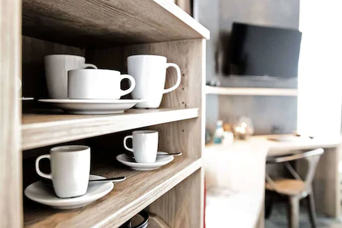 A wooden shelf with white cups and saucers.