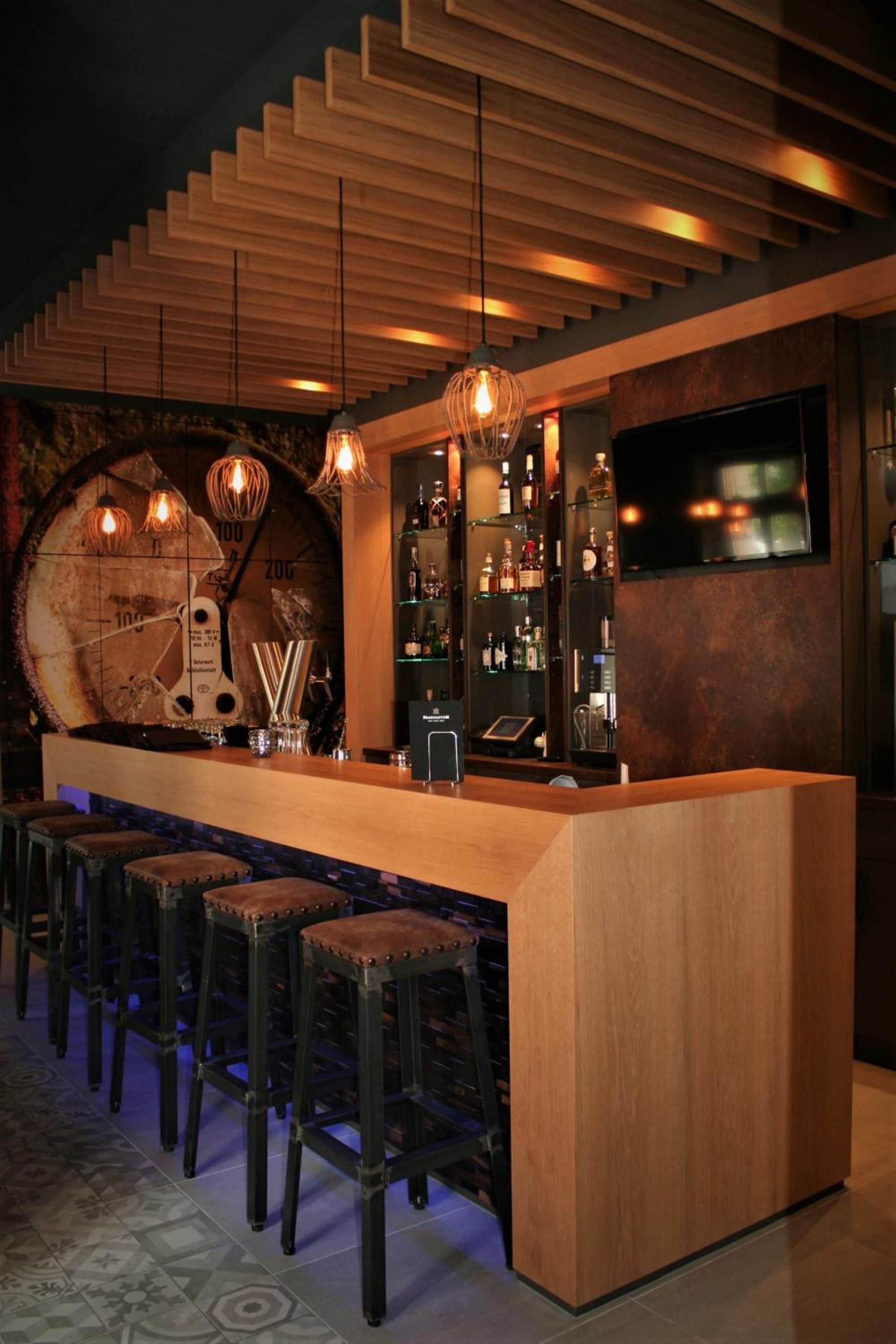 Eine Bar mit einer Holztheke, Hockstühlen und einer Wanduhr.