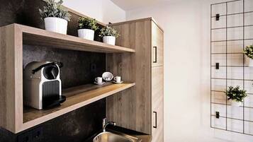 Una cocina moderna con armarios de madera, un lavamanos integrado y una cafetera.