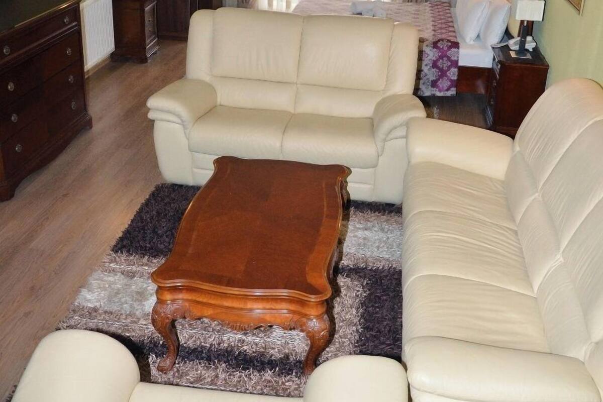 A living room with a beige sofa set, a wooden coffee table, and a television on a stand.
