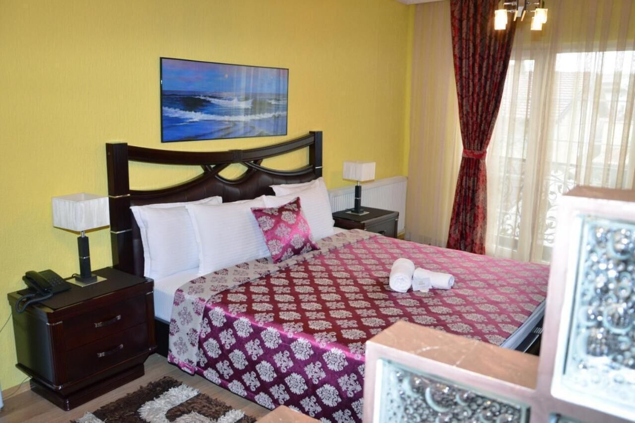 Une chambre d’hôtel avec un lit, une table de chevet avec un téléphone, une lampe et un tableau au mur.