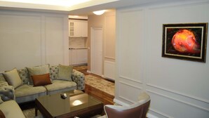 A living room with a sofa, coffee table, and a painting on the wall. - Hotel Begolli (Pristina)