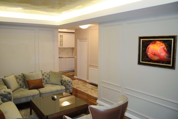 A living room with a sofa, coffee table, and a painting on the wall. - Hotel Begolli (Pristina)