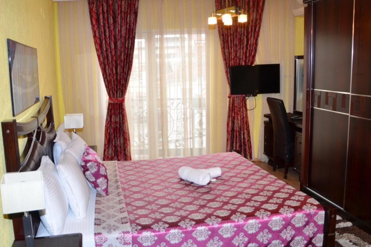 A hotel room with a bed, a desk, a chair, a TV, and a wardrobe.