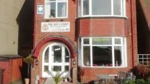 A two-story building with a red brick facade, a pitched roof, and a sign indicating it is a court.