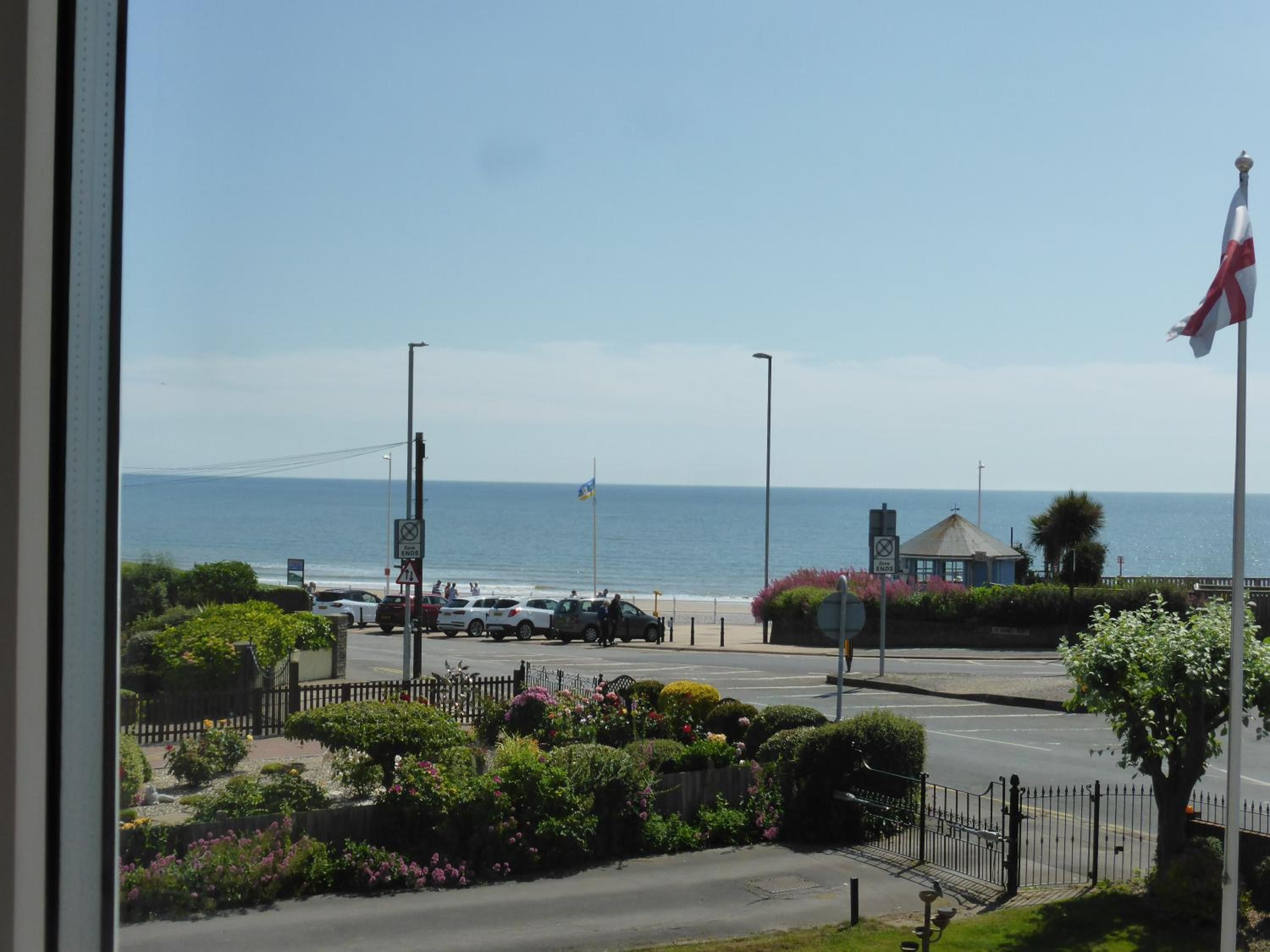 Una carretera costera con vista al mar, una bandera y un edificio con asta.