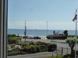 A coastal road with a view of the sea, a flag, and a building with a flagpole.