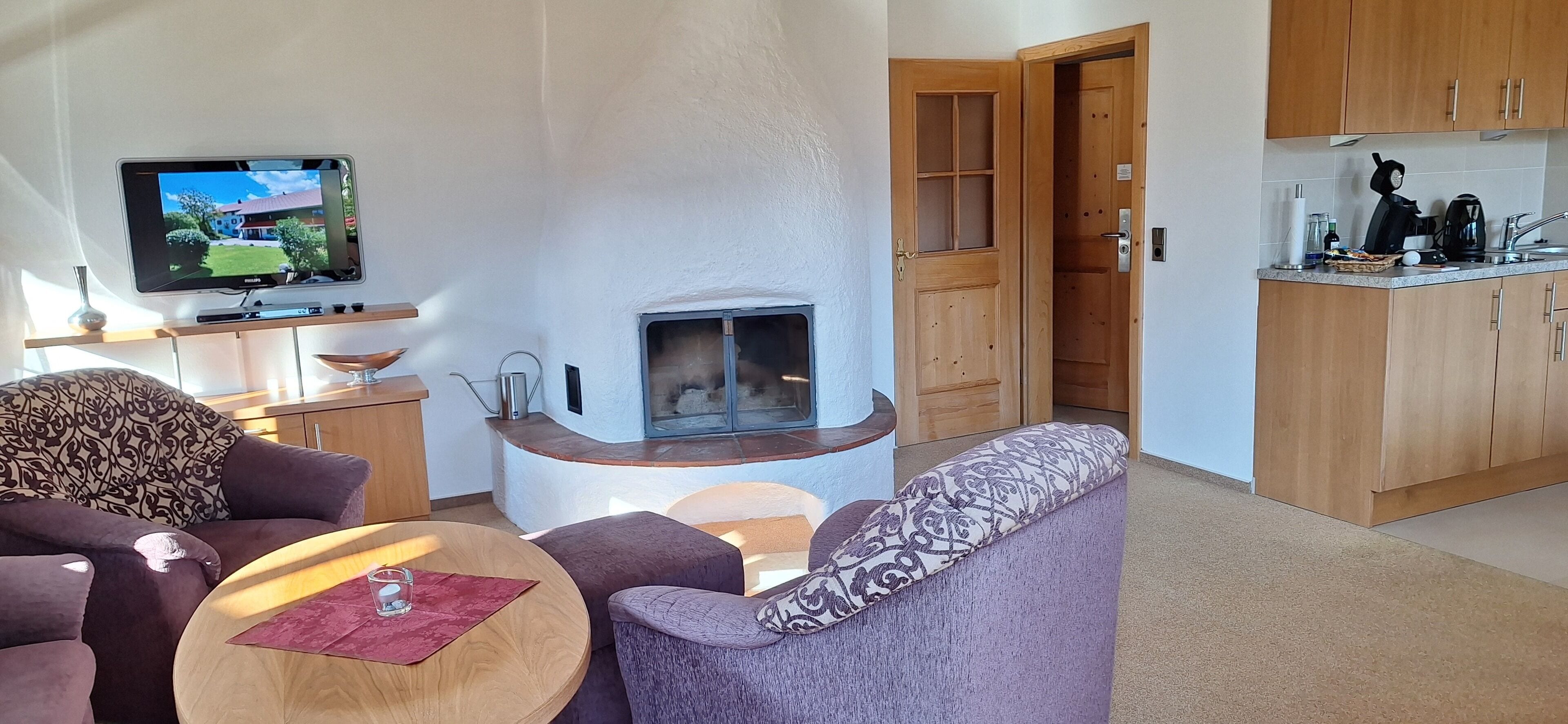Ein modernes Wohnzimmer mit Kamin, Fernseher und Küchenzeile.