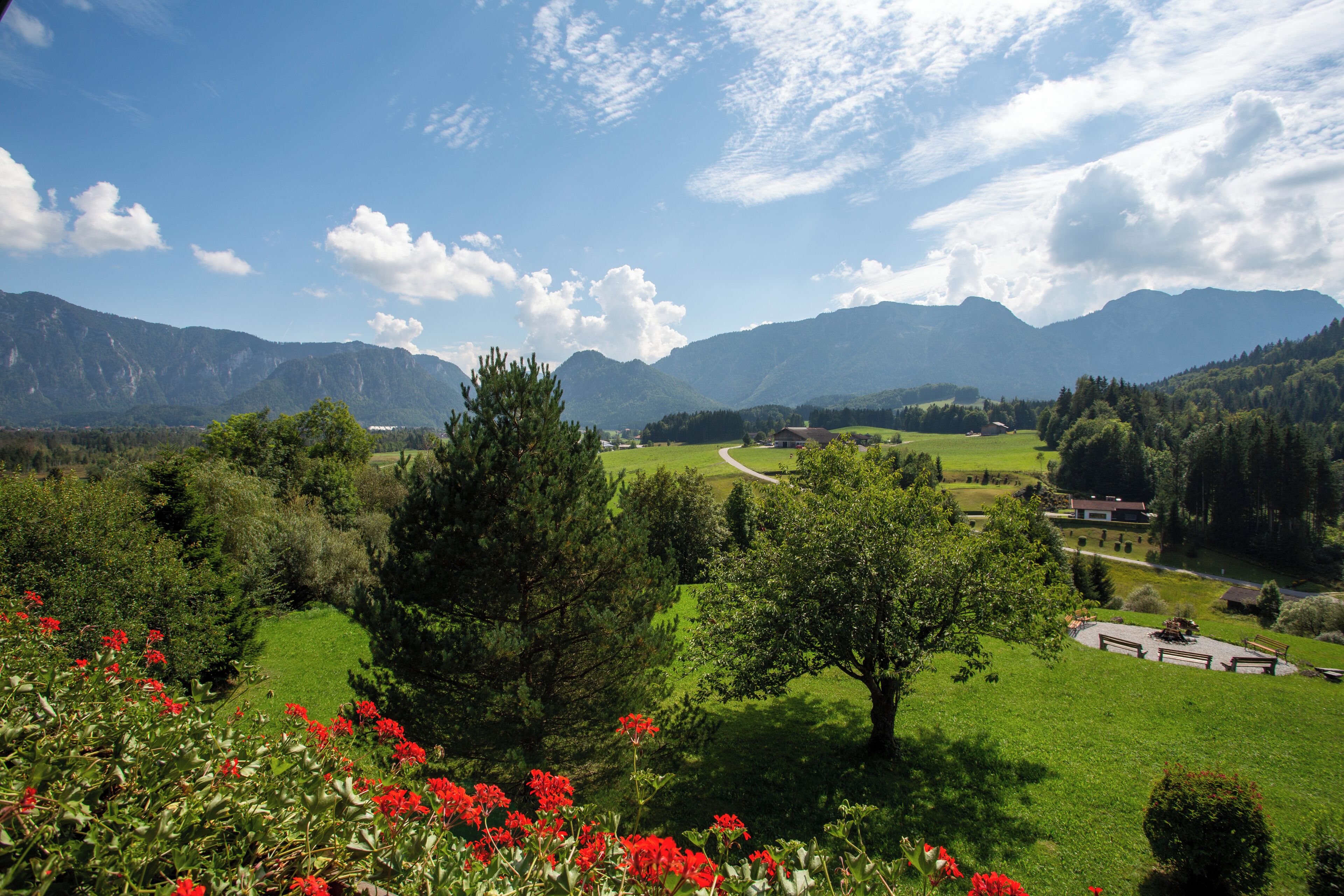Un paysage rural avec des montagnes, une route sinueuse et un petit bâtiment doté d’une zone dallée.