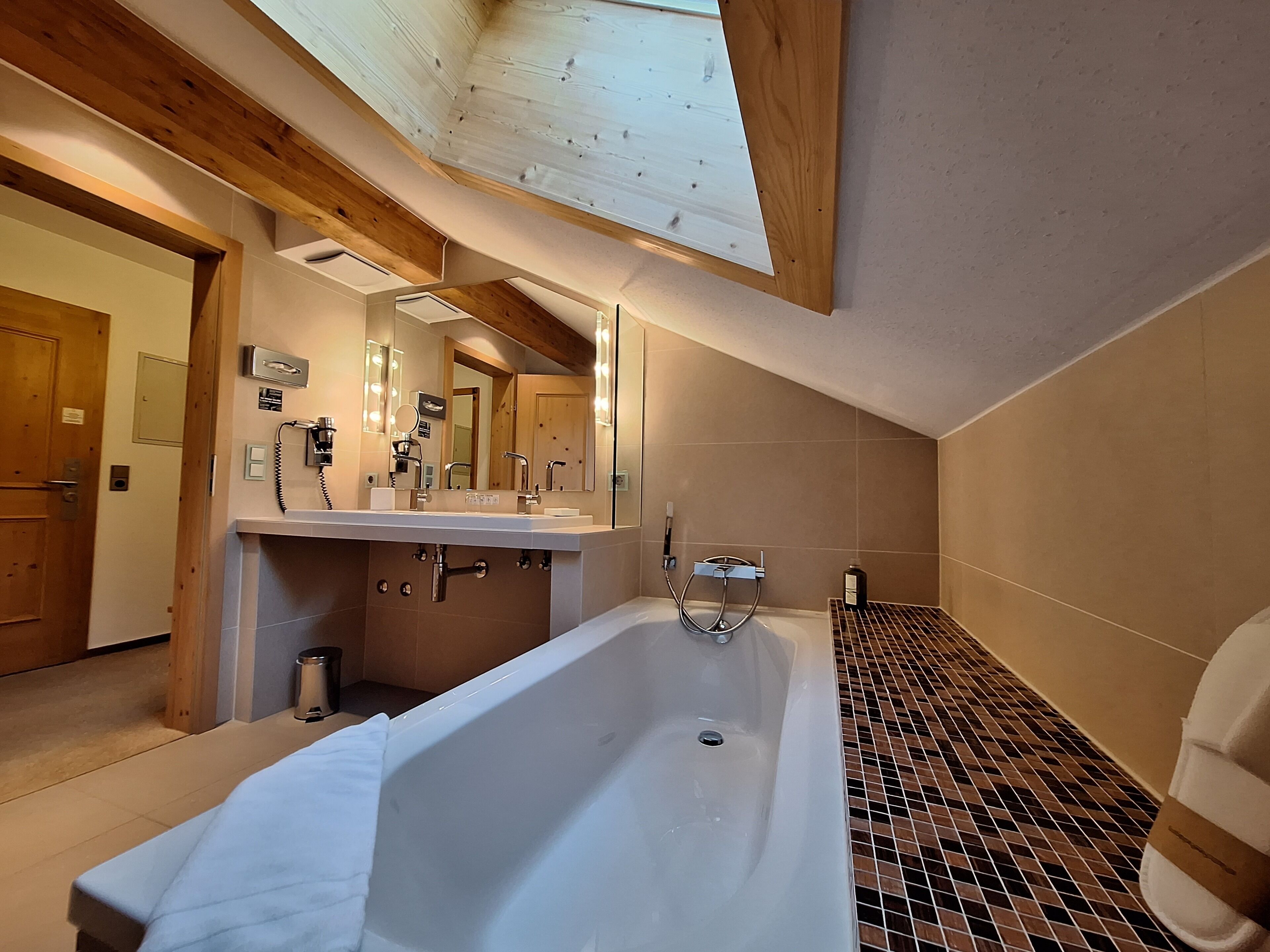 Een moderne badkamer met een ruime badkuip, een dubbele wastafel en een spiegel boven de wastafel.