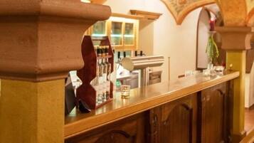 A bar area with a wooden counter, arched ceiling, and a view of the room in the background.