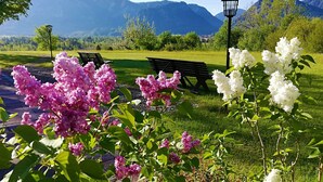 A park with benches, a lamp post, and flowering plants. - Hotel Heissenhof (Inzell)