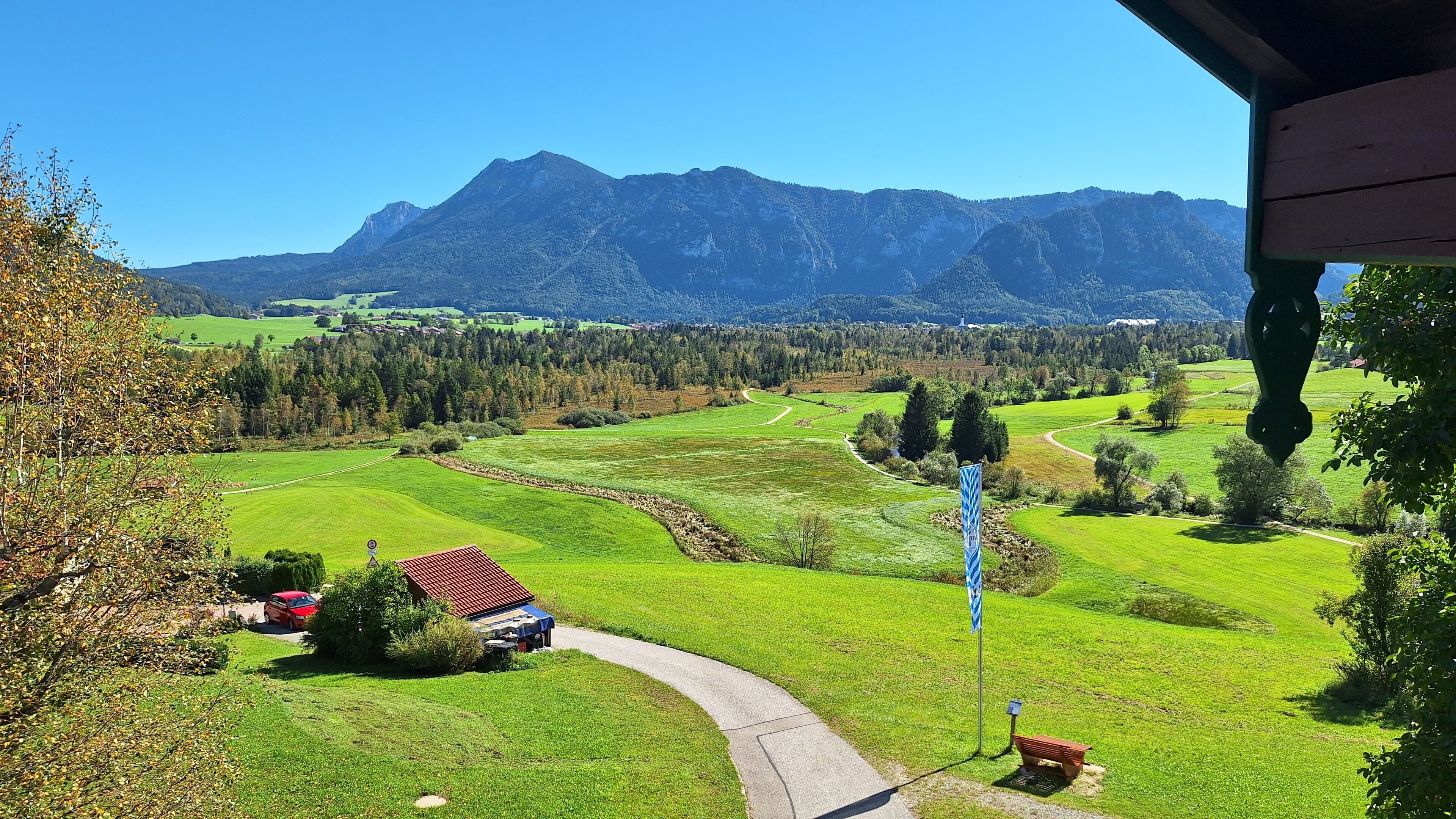 A rural landscape with a clear path, a small building, and a mountain range in the background.