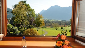A window view of a mountainous landscape with a clear sky. - Hotel Heissenhof (Inzell)