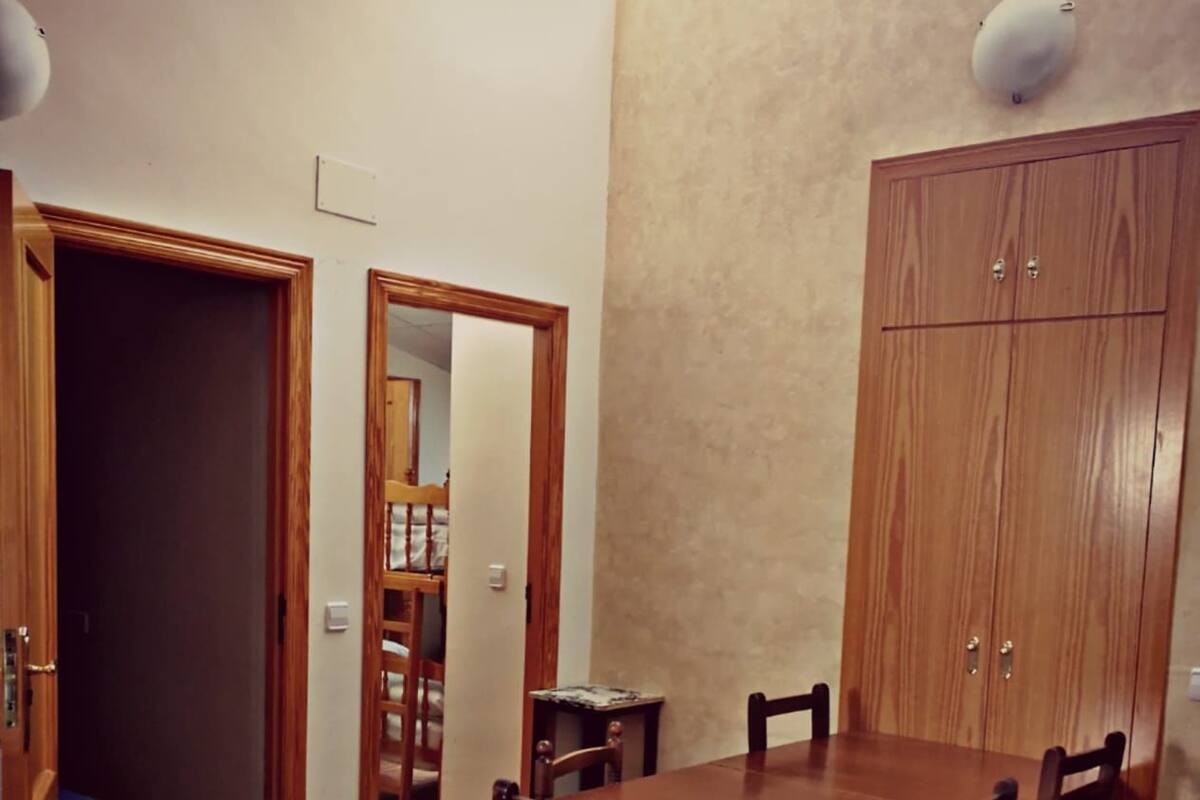 Ein Essbereich mit Holztisch und -stühlen, einem Schrank und Fliesenboden.