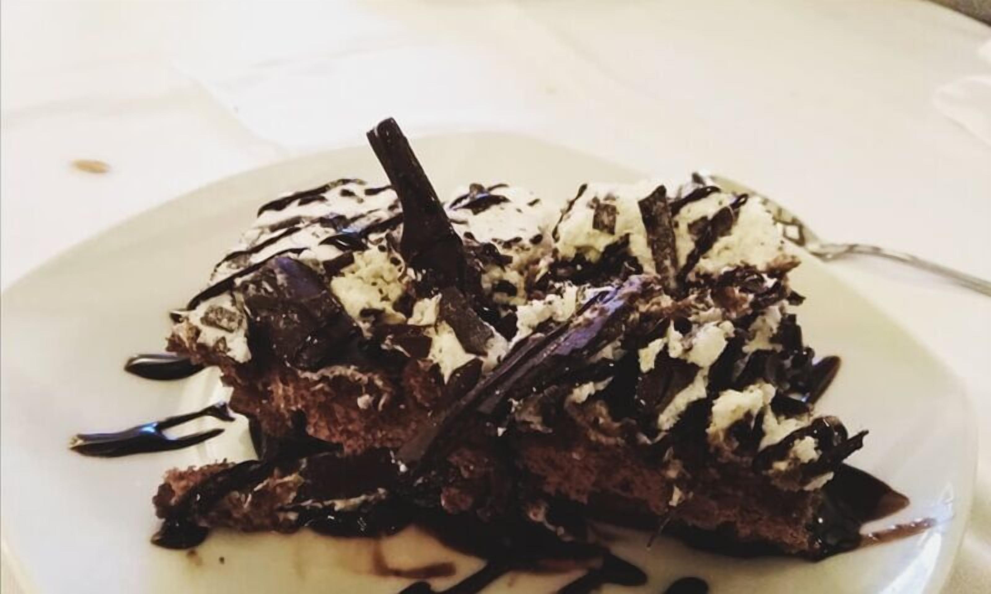 A dessert on a white plate with chocolate shavings and a chocolate drizzle.