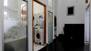 Una sala de lavandería con lavadora, secadora y tabla de planchar.