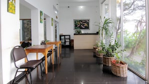 Un interior moderno con una mesa de recepción, plantas en macetas y obras de arte en las paredes.