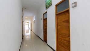Um corredor com portas de madeira, uma placa de número e um quadro na parede.