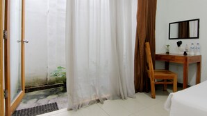Quarto de hotel com uma escrivaninha de madeira, uma cadeira, uma cama e banheiro com cortina de chuveiro.