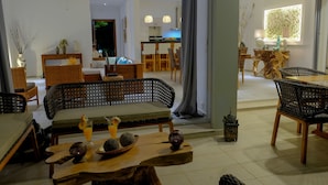 A modern living room with a sofa, chairs, and a dining area with a table and chairs. - Bel Horizon (Nosy Be)