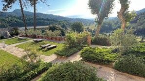Un jardín ajardinado con una estatua, un muro de piedra y vistas a colinas distantes.