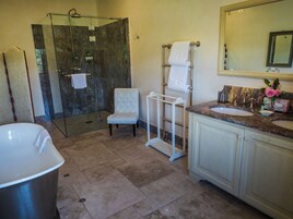 Un bagno con doccia, vasca, lavabo e una sedia.
