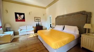 Una habitación de hotel con una cama grande, un sofá, un aparador y un cuadro en la pared.