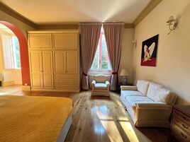 Una camera da letto con un letto grande, un divano, una poltrona e un armadio.
