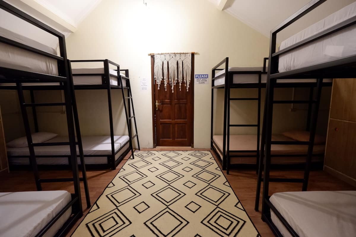 A dormitory room with bunk beds, a patterned carpet, and a door with a sign.