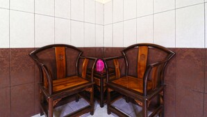 Rincón con dos sillas de madera y un objeto rosa sobre un suelo de baldosas.