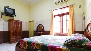 Un dormitorio con cama, armario de madera y televisor montado en la pared.