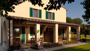 A two-story house with a covered patio, green shutters, and outdoor seating. - Agriturismo Villa Borgeri (Castagneto Carducci)