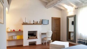 A bedroom with a bed, a desk, a chair, a television, and a fireplace. - Agriturismo Villa Borgeri (Castagneto Carducci)