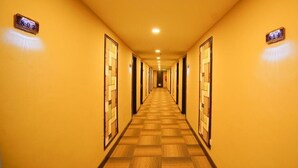 Un largo y estrecho pasillo de hotel con suelo de madera y paredes amarillas.