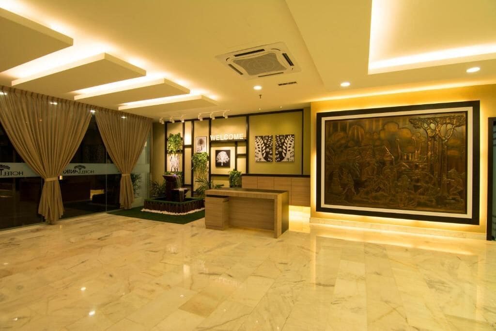 A hotel lobby with a marble floor, a reception desk, a large wall mural, and a 'Welcome' sign.