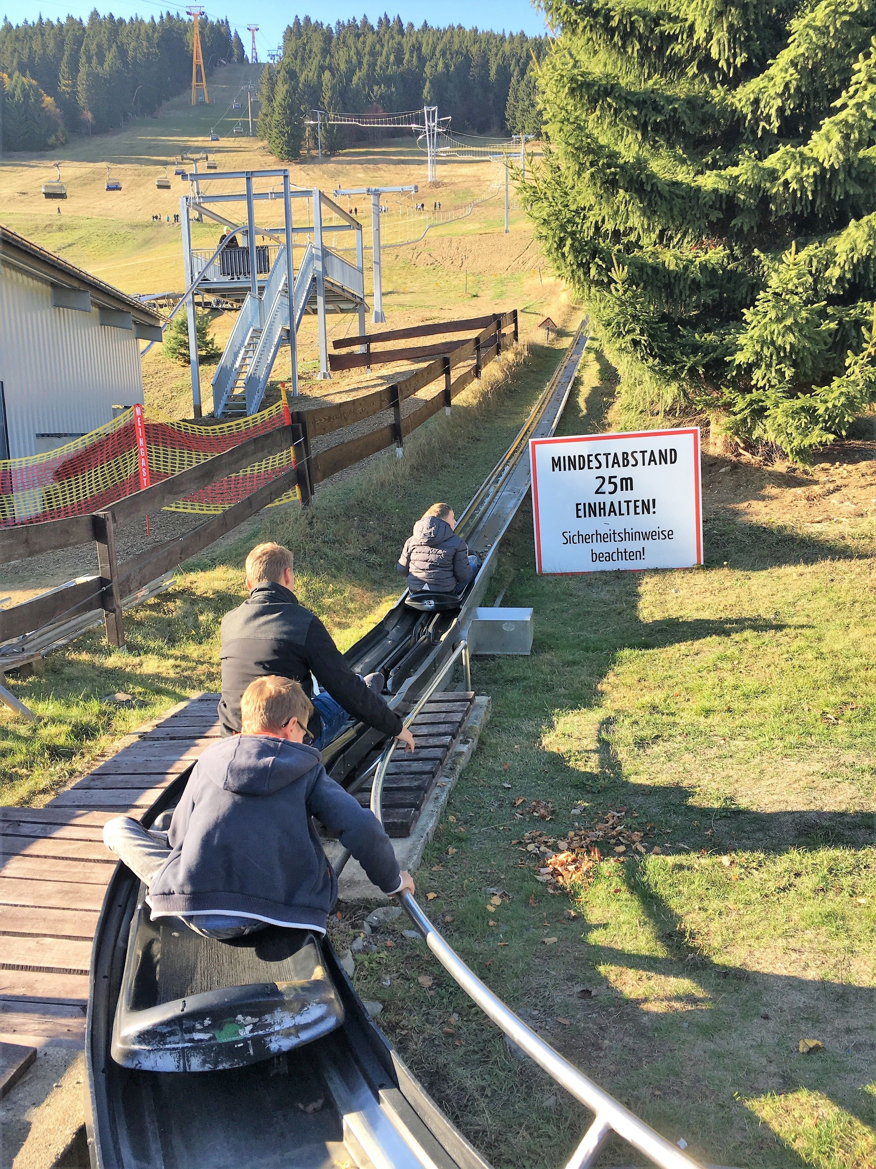 A ski lift with passengers, a sign indicating a 25m height, and a forested background.