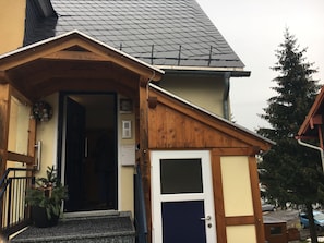 A building with a wooden facade, a dark roof, and a small entrance with steps.